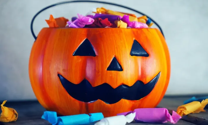 Pumpkin with candy on gray background